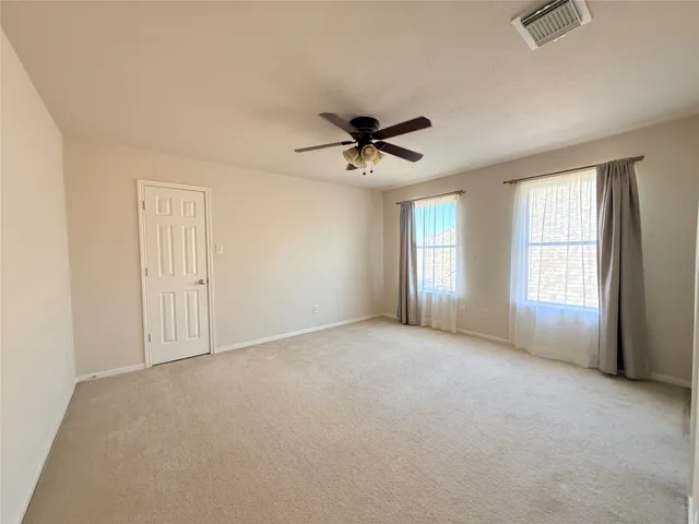 an empty room with windows and ceiling fan