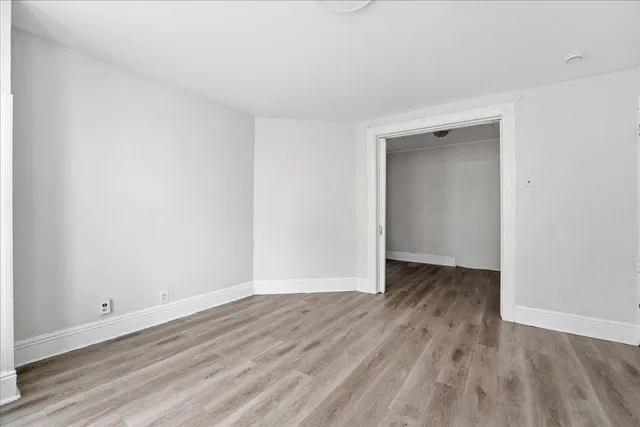 a view of an empty room with wooden floor and closet