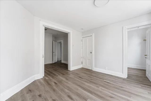 a view of an empty room with wooden floor and closet