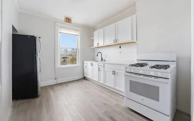 a kitchen with granite countertop white cabinets and black appliances