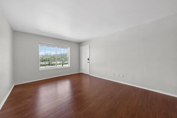 an empty room with wooden floor and window
