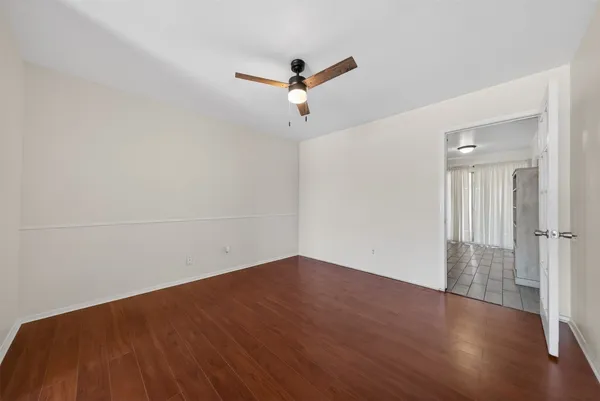an empty room with wooden floor ceiling fan and windows