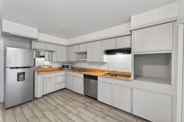 a kitchen with stainless steel appliances granite countertop a refrigerator a sink and white cabinets