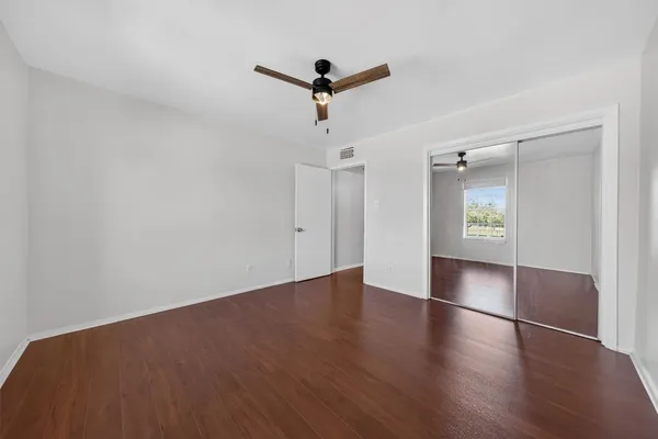 a view of empty room with wooden floor and ceiling fan