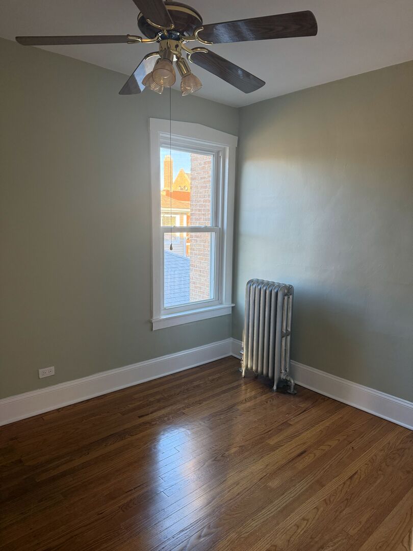 4253 North Austin Avenue, Unit 2 Chicago, IL 60634 - Photo 8 of 9 an empty room with wooden floor fan and windows