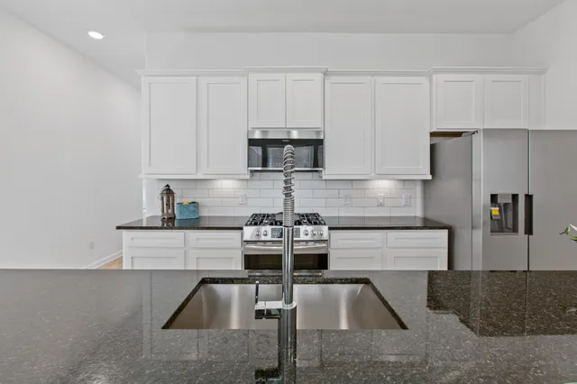 a kitchen with stainless steel appliances granite countertop a sink stove refrigerator and cabinets