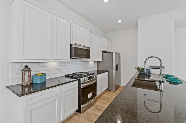 a kitchen with granite countertop a sink stove and refrigerator