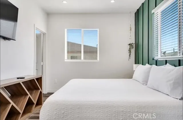 a bedroom with a bed a flat screen tv and windows