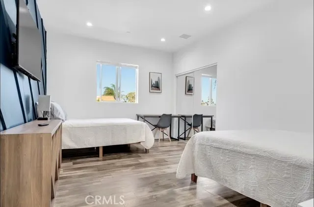 a bedroom with a bed a couch and a flat tv screen on the dresser