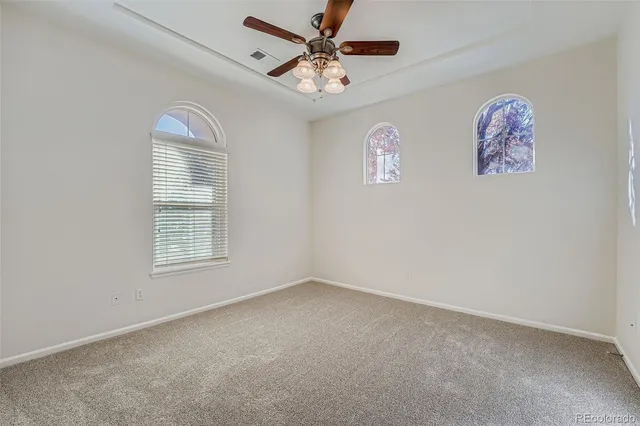 an empty room with windows and fan