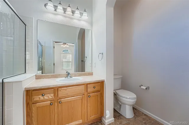 a bathroom with a granite countertop sink mirror vanity and toilet