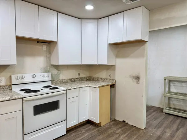 a kitchen with cabinets appliances and a wooden floor