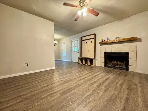 a view of empty room with wooden floor fireplace and fan