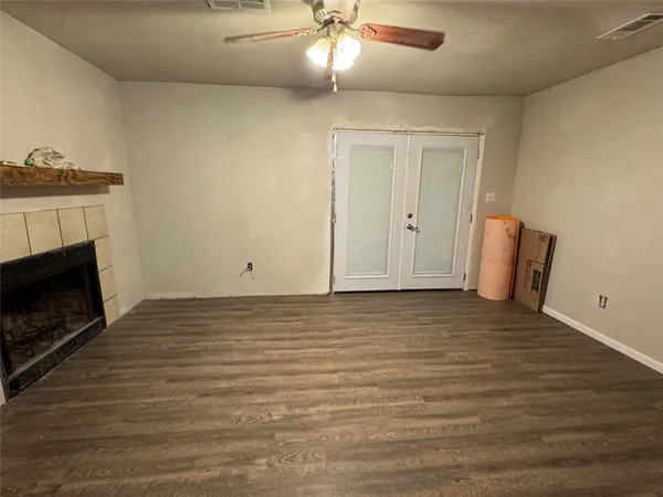 a view of an empty room with a fireplace and chandelier fan