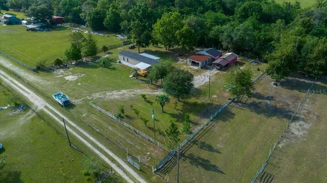 an aerial view of residential houses with outdoor space and trees