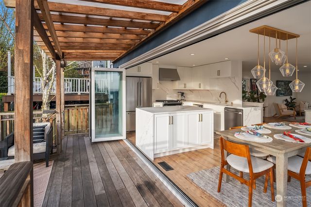 a kitchen with stainless steel appliances granite countertop a stove top oven a sink dishwasher and a dining table with wooden floor