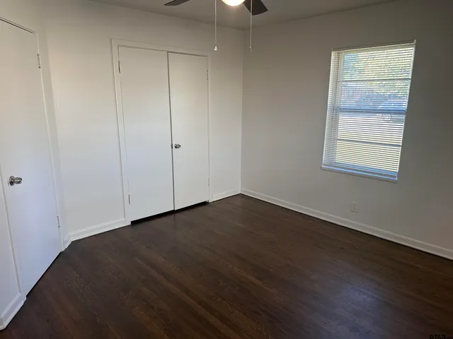 an empty room with wooden floor cabinet and windows