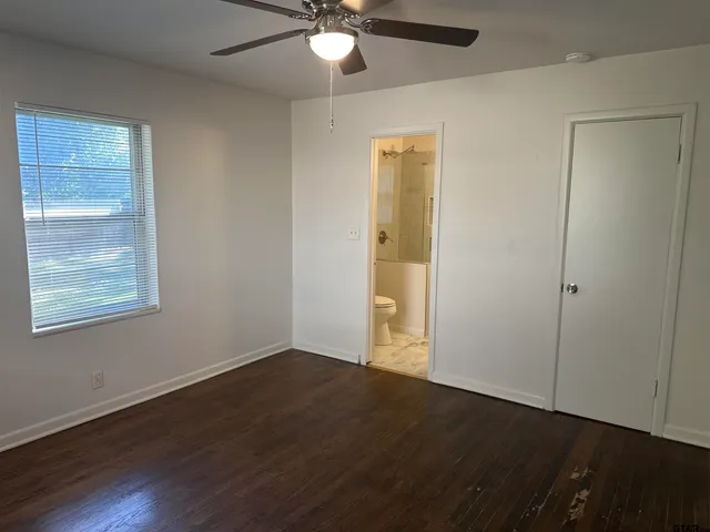 an empty room with wooden floor closet and windows
