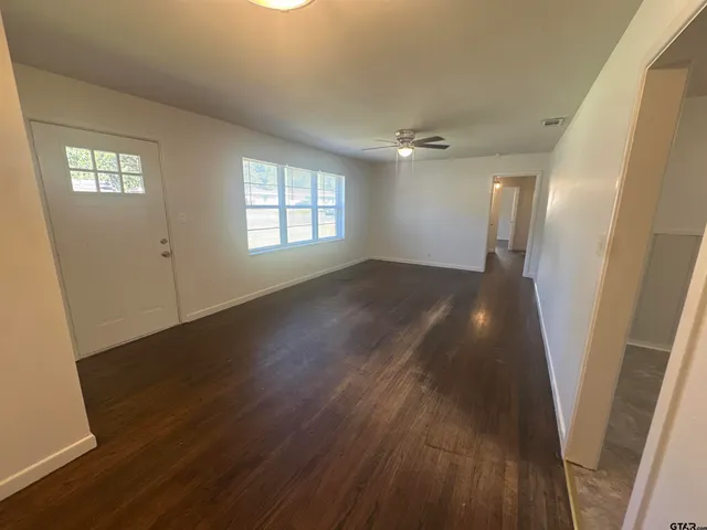an empty room with wooden floor and windows
