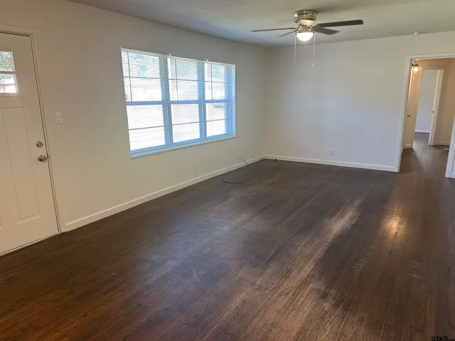 an empty room with wooden floor and windows