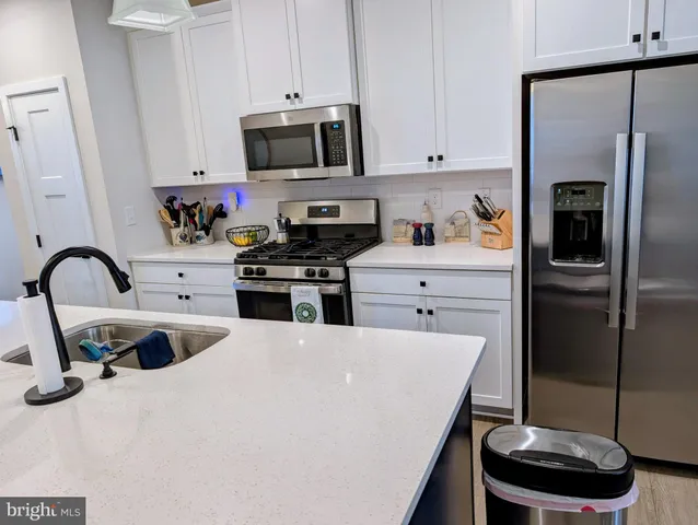 a kitchen with stainless steel appliances a stove a sink a refrigerator and cabinets