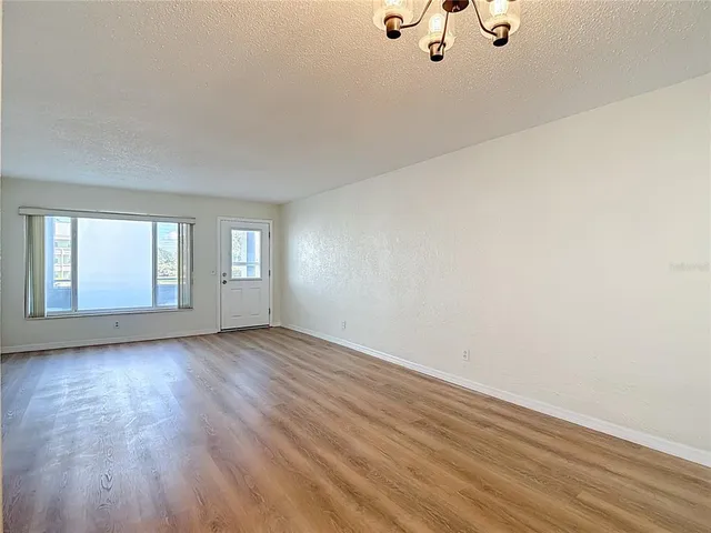 an empty room with wooden floor cabinet and windows