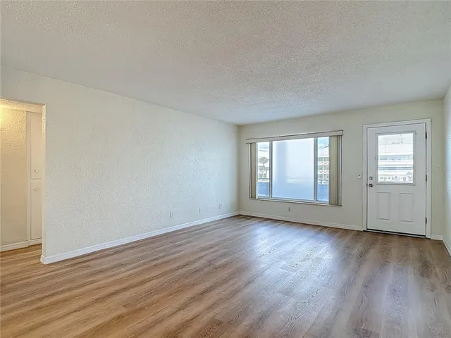 a view of an empty room with wooden floor and window