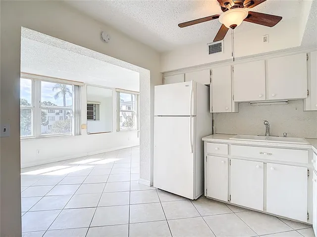 a kitchen with a refrigerator a stove top oven and cabinets