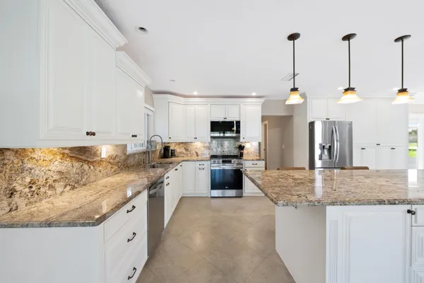 a kitchen with granite countertop white cabinets and white appliances