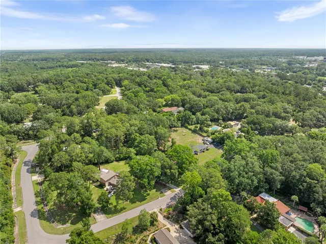 an aerial view of residential houses with outdoor space and trees