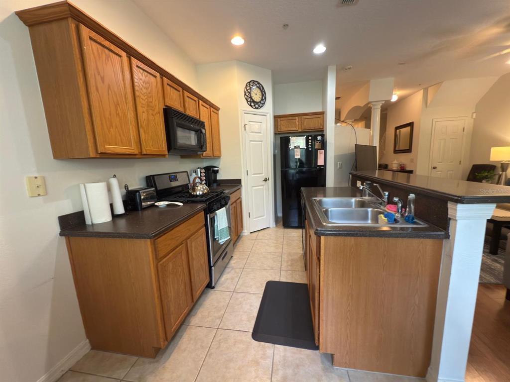 879 Assembly Court Reunion, FL 34747 - Photo 17 of 46 a kitchen with stainless steel appliances granite countertop a stove a sink a refrigerator and a microwave