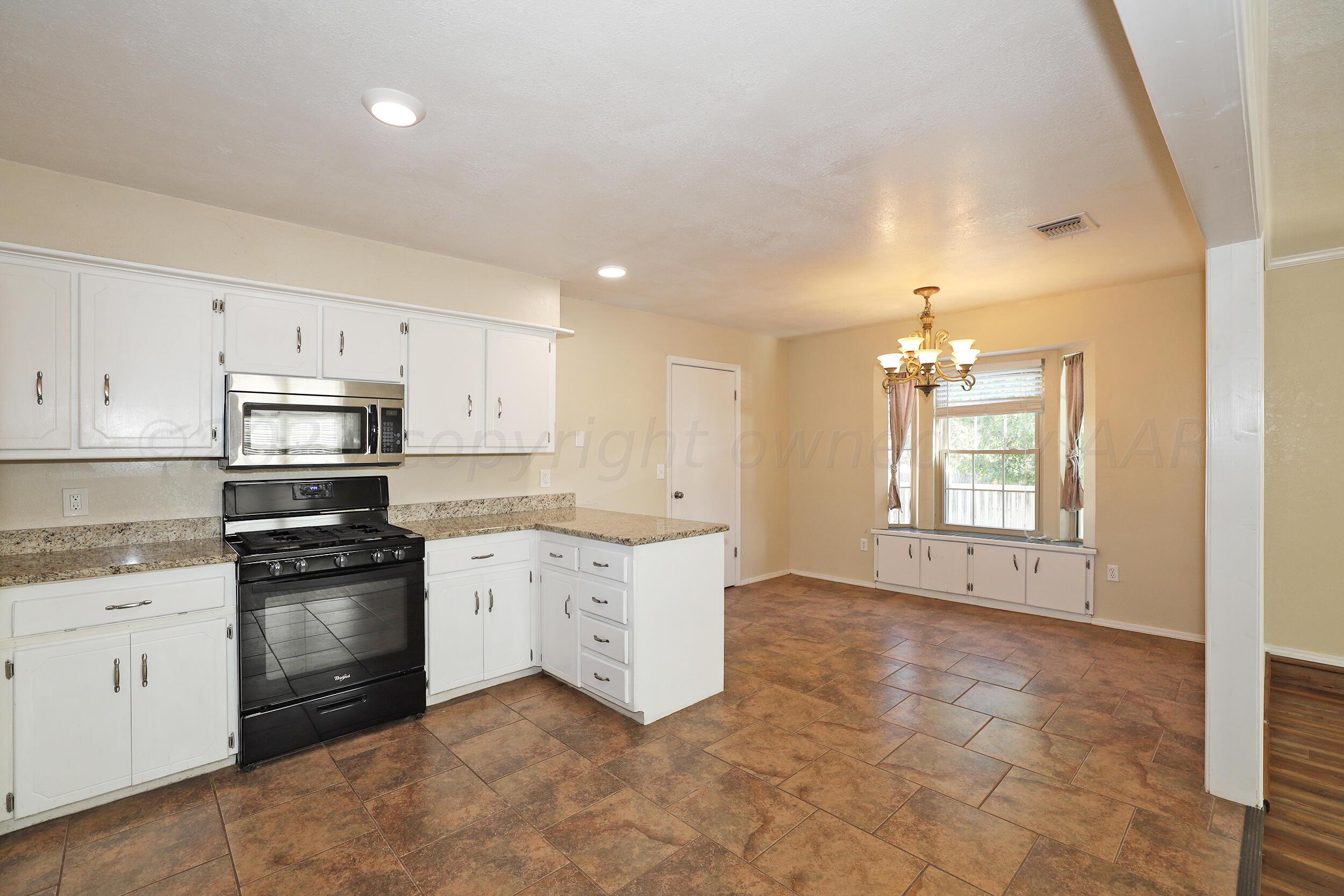 2905 Salem Drive Amarillo, TX 79110 - Photo 7 of 29 a large kitchen with granite countertop a stove top oven a sink a window and white cabinets