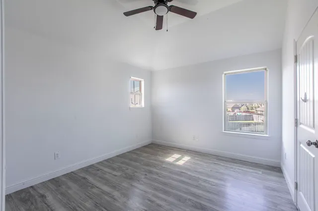 a view of an empty room with a window and wooden floor