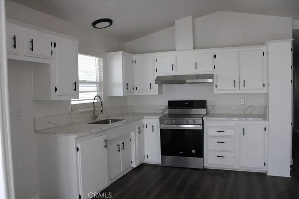 a kitchen with stainless steel appliances granite countertop a stove a sink and white cabinets