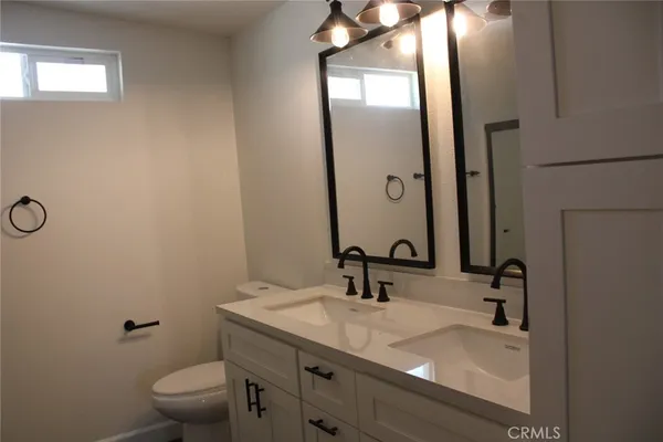 a bathroom with a granite countertop sink a toilet and a mirror