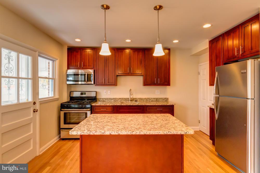 6146 Marlora Road Baltimore, MD 21239 - Photo 3 of 27 a kitchen with kitchen island a counter top space a sink a refrigerator and cabinets