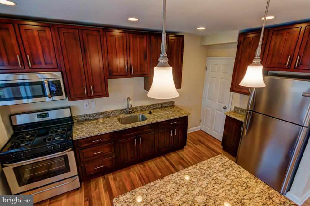6146 Marlora Road Baltimore, MD 21239 - Photo 4 of 27 a kitchen with stainless steel appliances granite countertop wooden cabinets a stove a sink and a microwave
