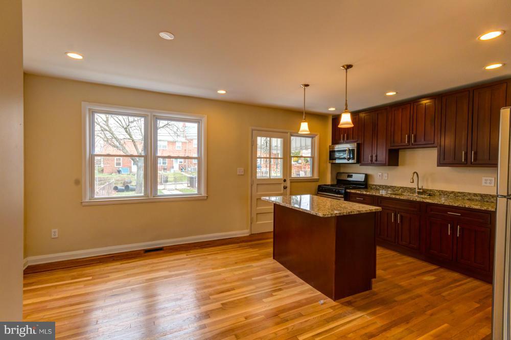 6146 Marlora Road Baltimore, MD 21239 - Photo 7 of 27 a kitchen with stainless steel appliances granite countertop wooden cabinets a stove a sink and a window