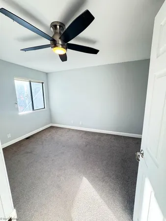 an empty room with windows and fan