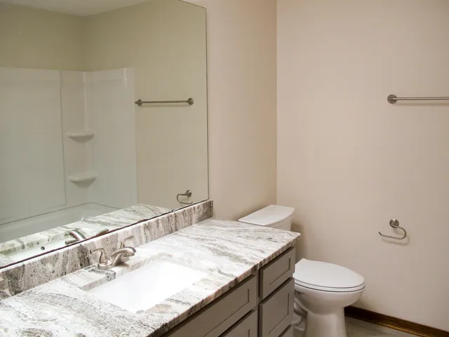 a bathroom with a granite countertop sink a toilet and a mirror