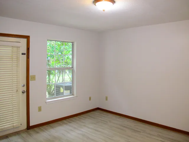 an empty room with wooden floor cabinet and windows