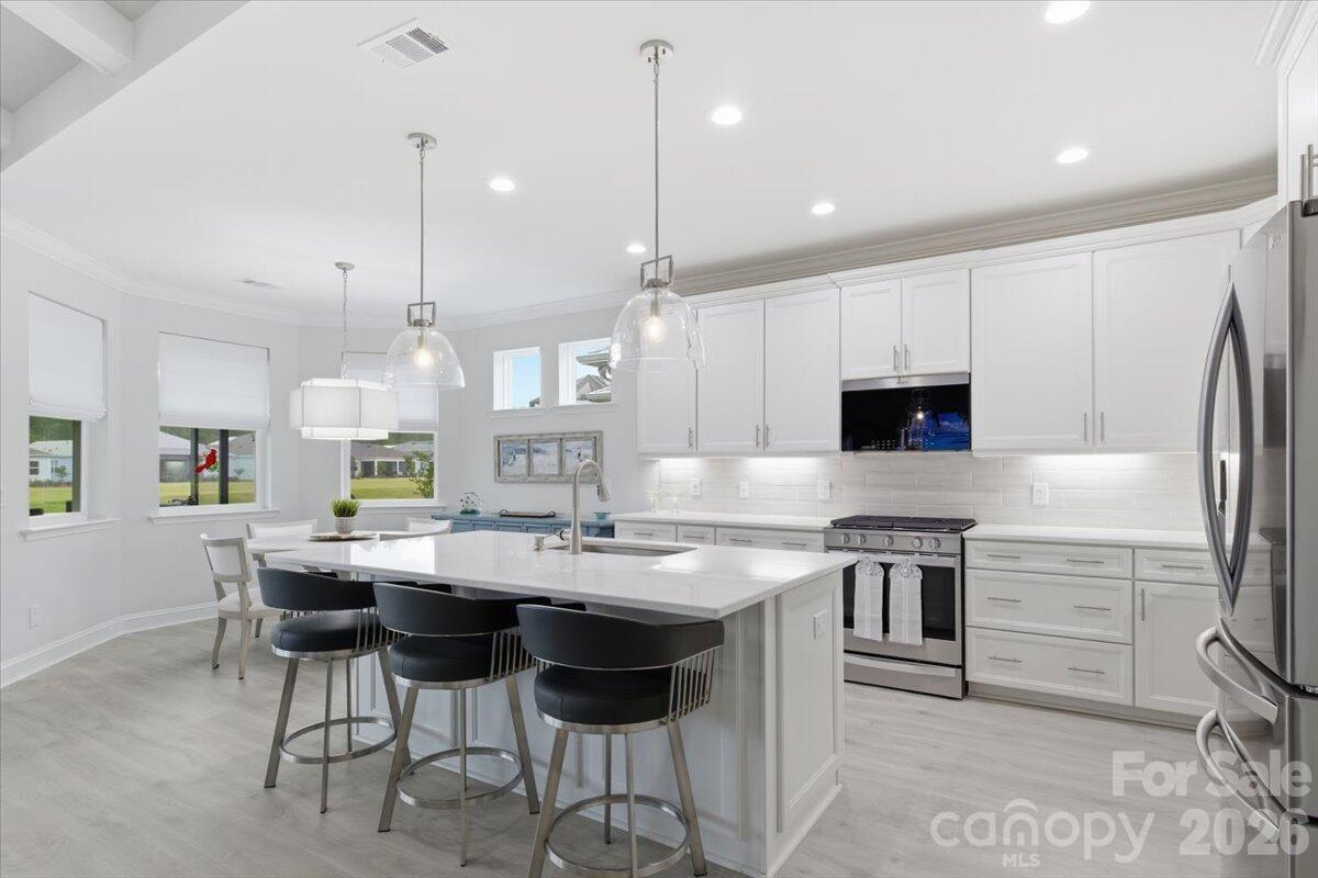 859 Ocean Hammock Loop Hardeeville, SC 29927 - Photo 10 of 33 a kitchen with stainless steel appliances kitchen island granite countertop a sink a stove a refrigerator and chairs
