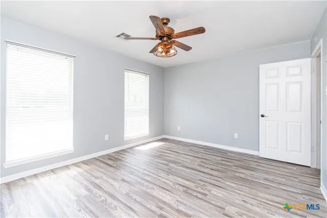 a view of a room with wooden floor and a ceiling fan
