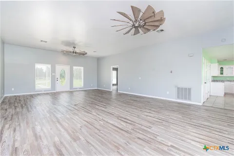 a view of an empty room with window and wooden floor