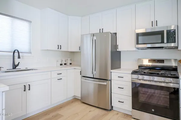 a kitchen with white cabinets stainless steel appliances and sink