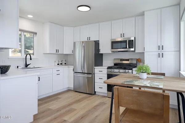 a kitchen with refrigerator a stove a sink cabinets and wooden floor