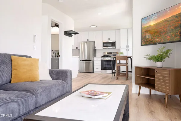 a living room with stainless steel appliances furniture and a flat screen tv