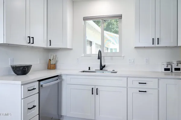 a kitchen with white cabinets and window