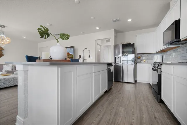 a kitchen with stainless steel appliances a sink dishwasher a refrigerator a microwave oven with cabinets and wooden floor