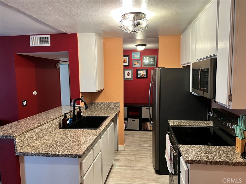 1723 Cedar Avenue, Unit 102 Long Beach, CA 90813 - Photo 7 of 22 a kitchen with granite countertop a sink and refrigerator
